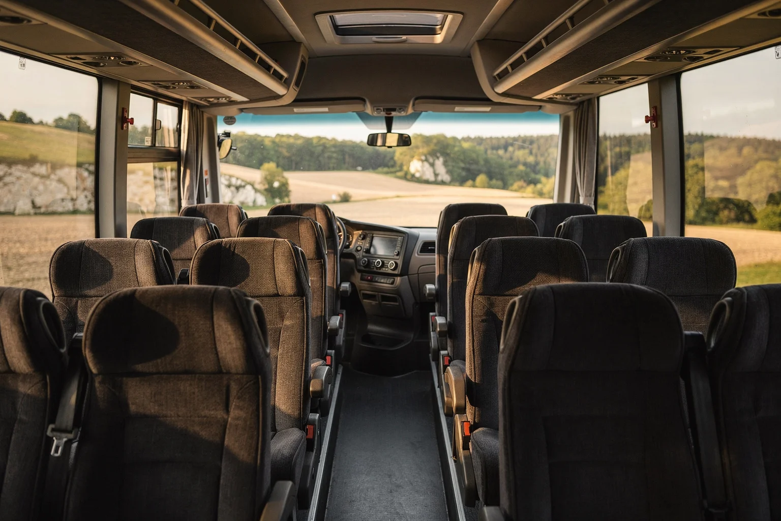 Empty coach seats beside windows looking onto green countryside