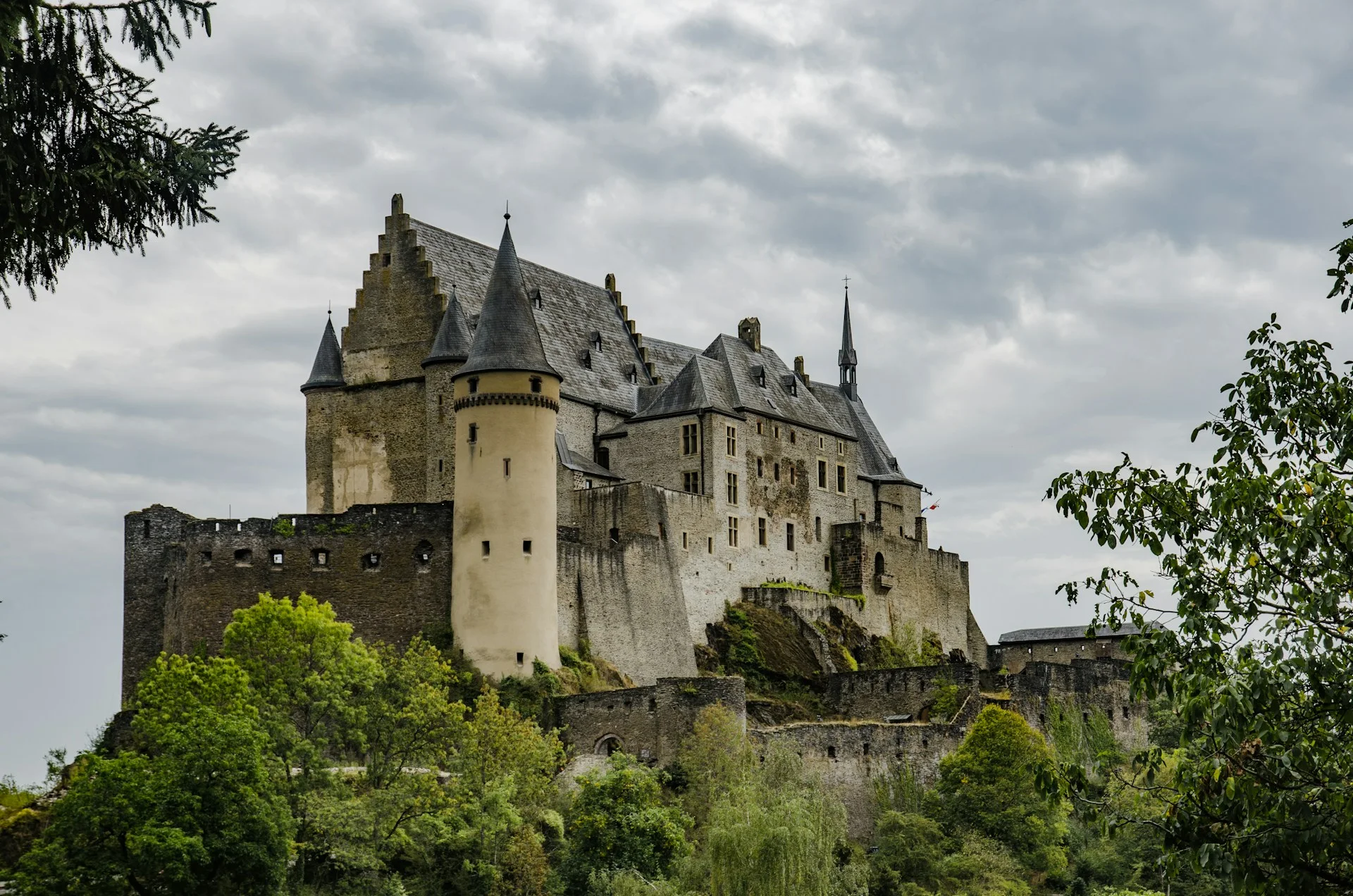 Vianden Castle above a wooded hillside under a cloudy sky
